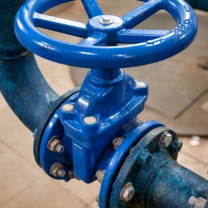 Blue cast iron butterfly valve with flanged connection and handwheel control in an industrial pipeline system.