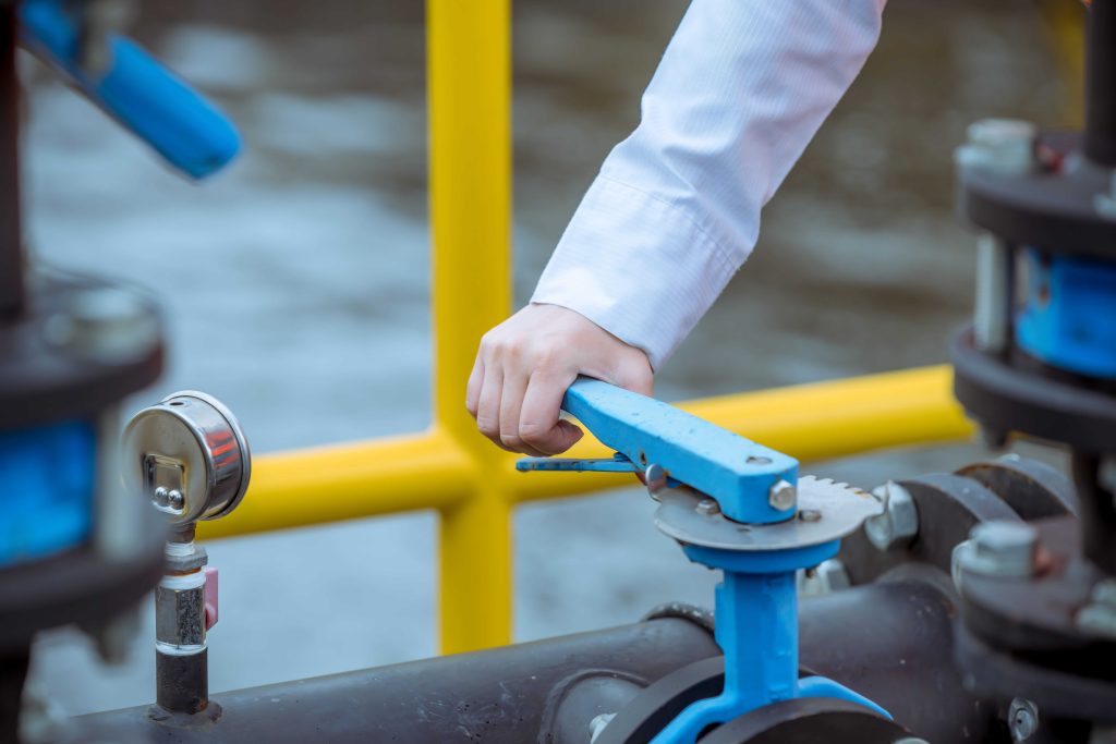 Engineer operating a ductile iron butterfly valve with a blue lever handle in a process pipeline system.