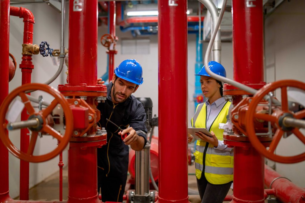 Factory engineers inspecting butterfly valves and pipeline system inside industrial production facility