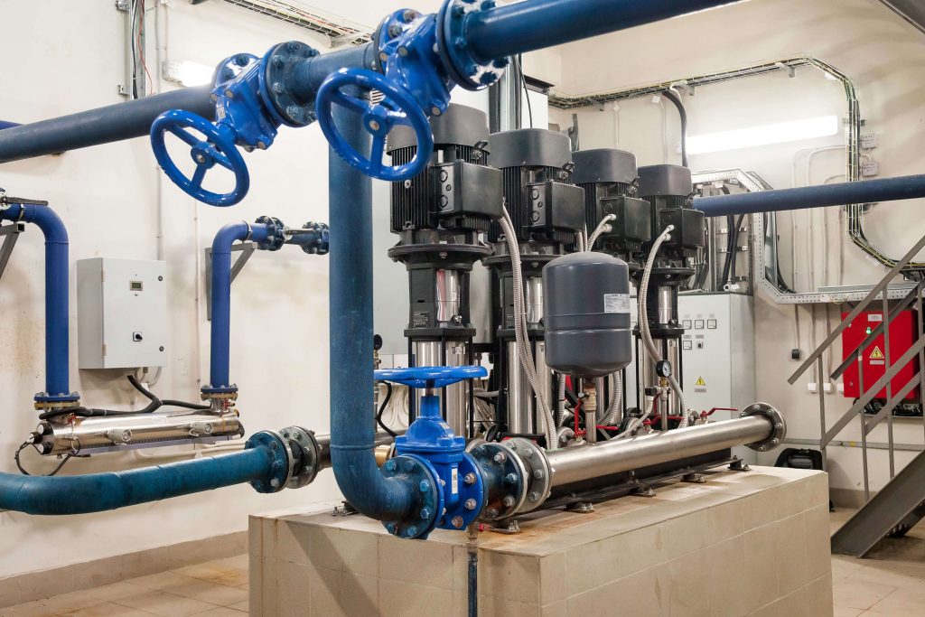 Butterfly valves installed in blue industrial pipelines within a mechanical room