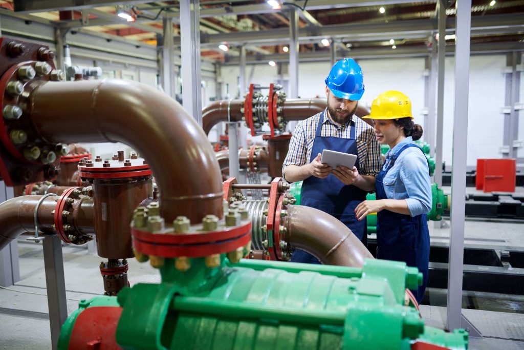 Engineers inspecting an operational pipeline system with mounted butterfly valves in a water treatment or process plant.