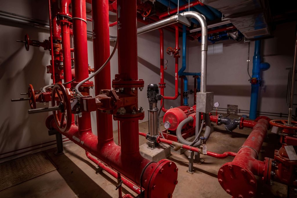 Industrial piping network with red and blue steel pipelines and ball valves in mechanical plant