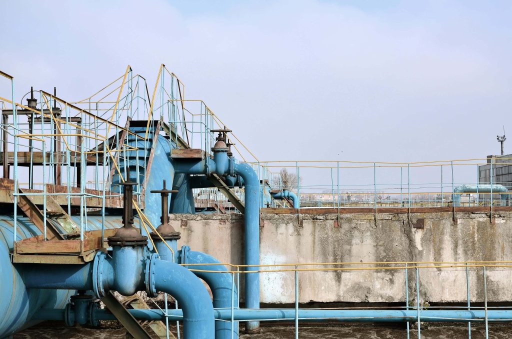 Large blue industrial pipelines with gate and butterfly valves in a water treatment plant used for flow control and distribution.