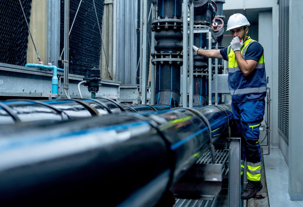 Blue flanged vented ball valve on a metal workbench inside a workshop, showing precision machining and industrial coating details.