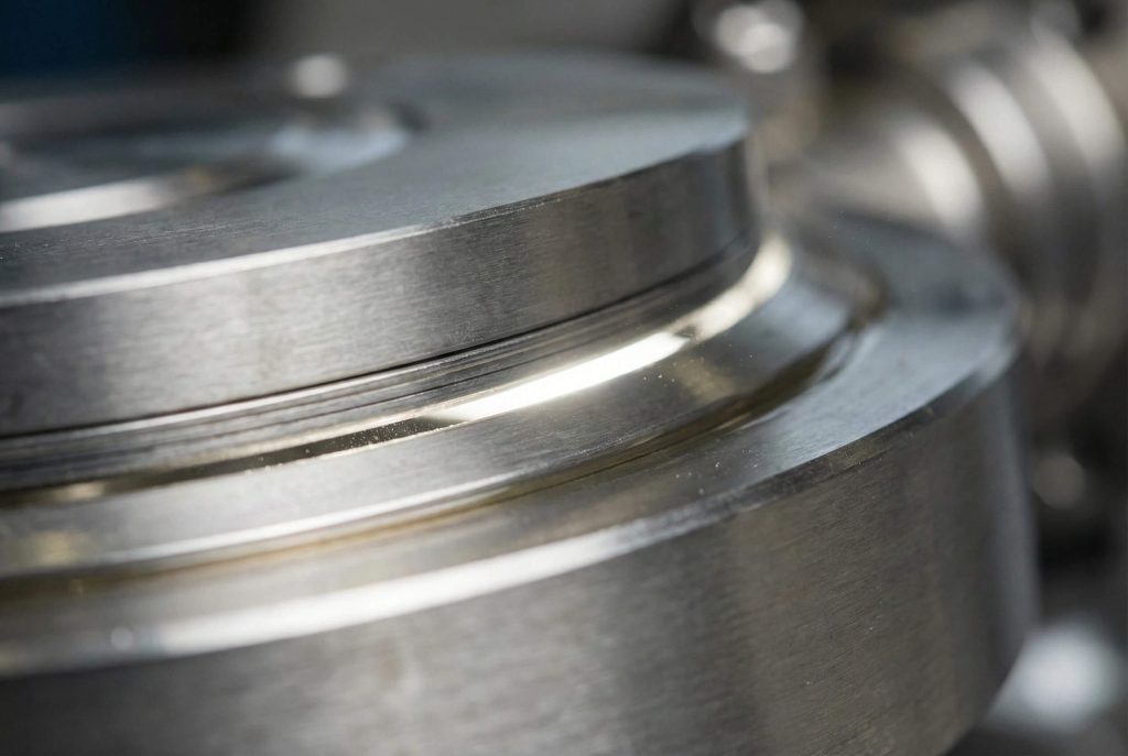 Macro photography of a stainless steel butterfly valve disc and laminated seal ring just as it unseats, showing the eccentric design gap.