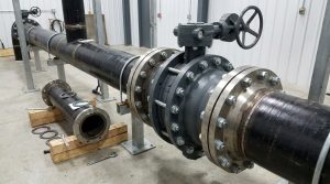 A lug body butterfly valve installed between two pipe flanges in an industrial piping system, with full-pattern tapped lugs independently securing each flange and a removable downstream pipe section visible beside the maintenance area.